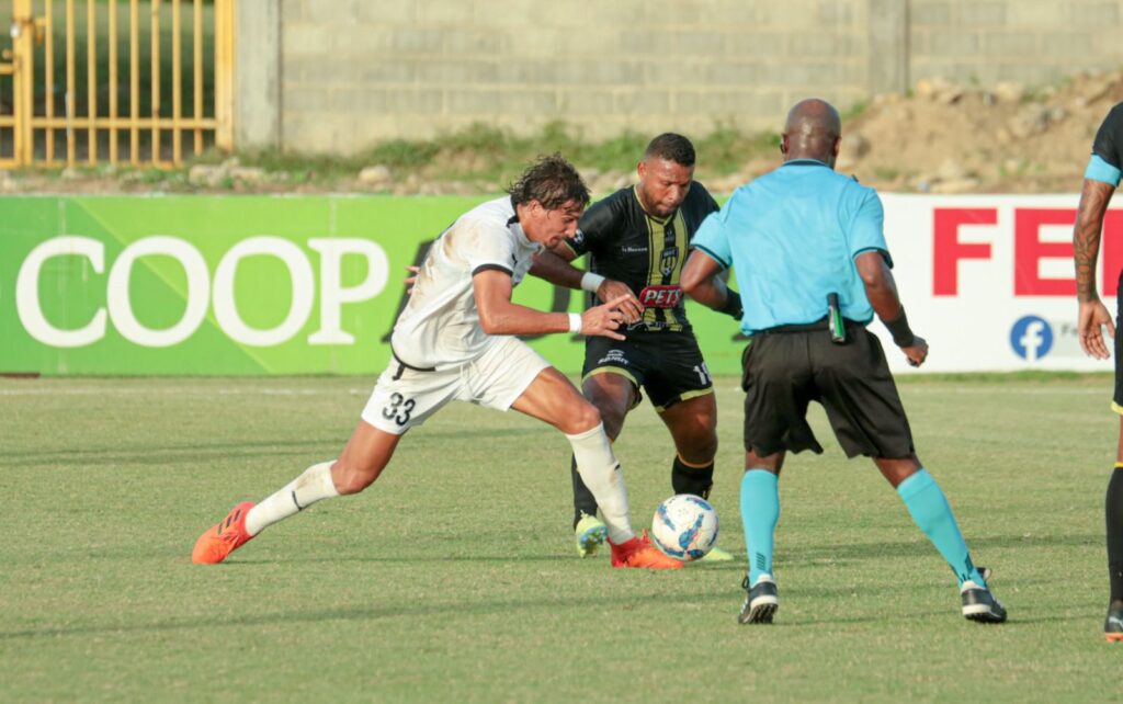 Facundo Gichón dde Cibao FC (de blanco) pelea una pelota a Alejando Carrera de Moca FC